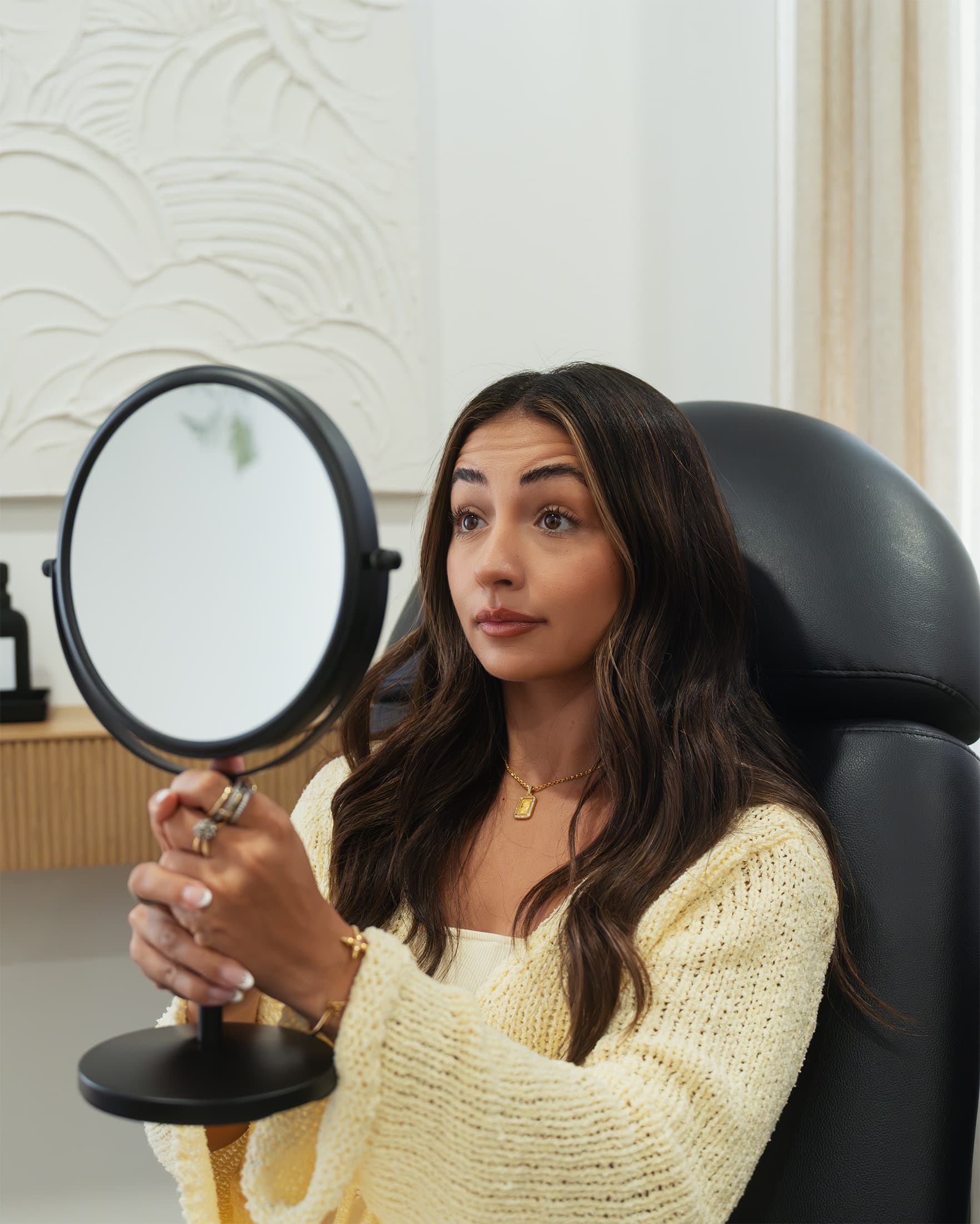 A NakedMD client admiring her refreshed forehead in the studio